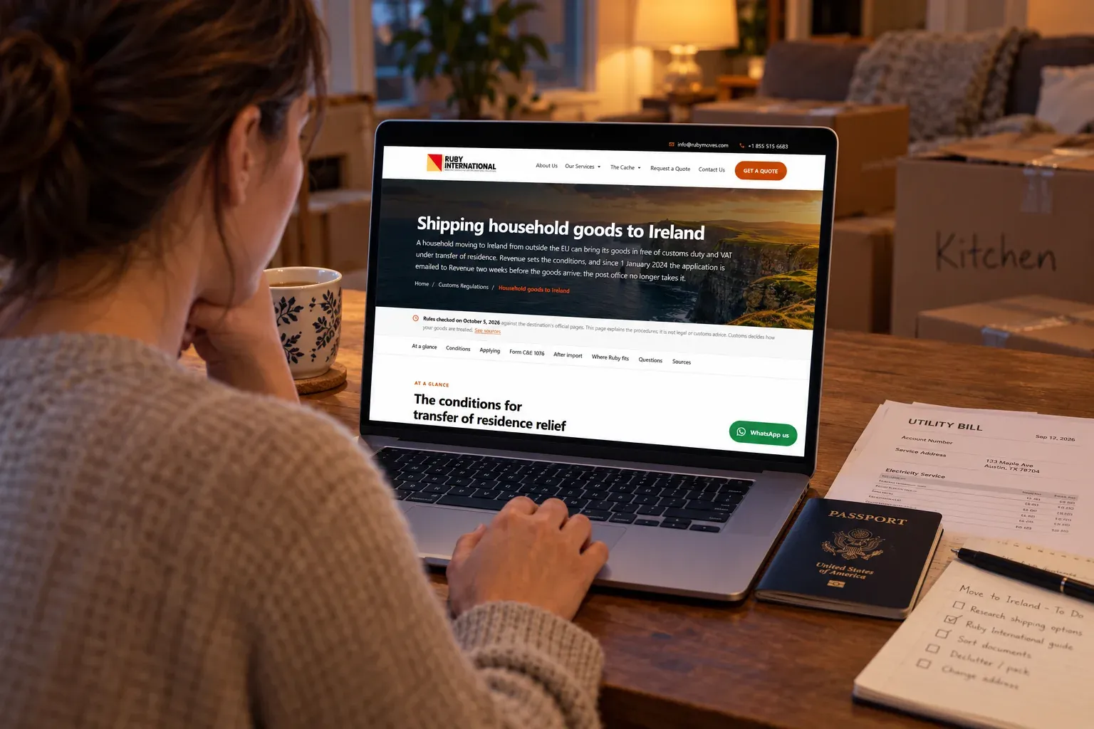 Someone at a laptop open to Ruby International's Ireland guide, a passport and a utility bill beside it, in a living room mid-pack